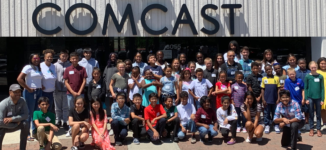 Slide Image - students and team posing infront of comcast headquarters