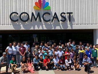 team and students posing infront of comcast headquarters